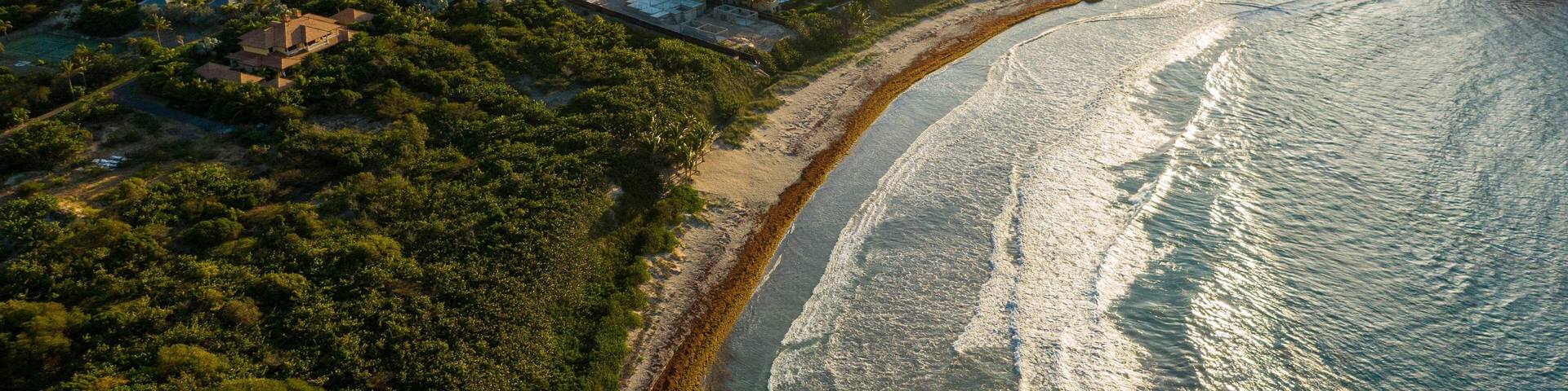A coastal landscape with a beach, houses, and a bay with islands.