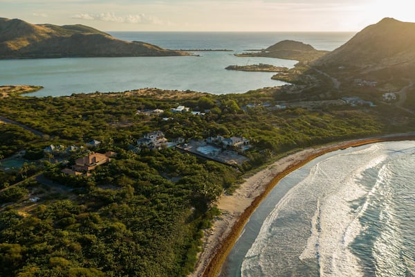 Un paysage côtier avec une plage, des maisons et une baie parsemée d’îles.