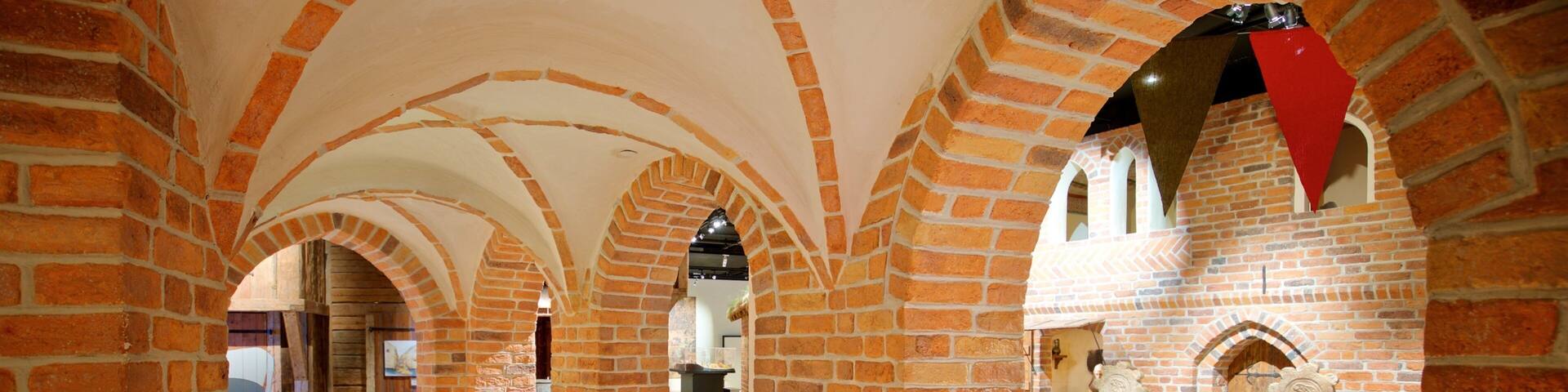 A brick corridor with arches and a cobblestone floor.