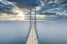 Un grand pont suspendu enjambant une étendue d’eau large, avec un ciel nuageux au-dessus.