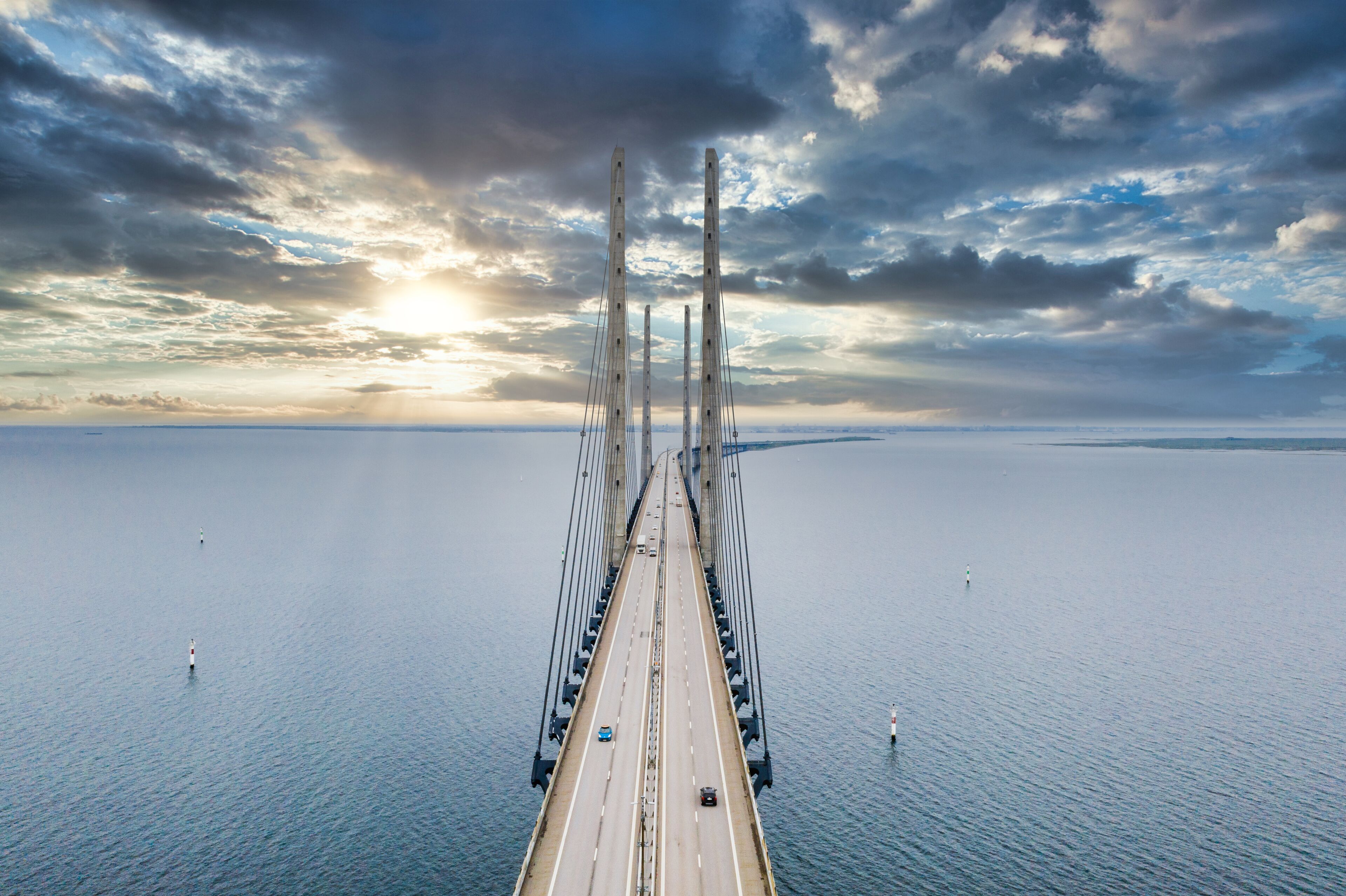 A large suspension bridge spanning a wide body of water with a cloudy sky above.