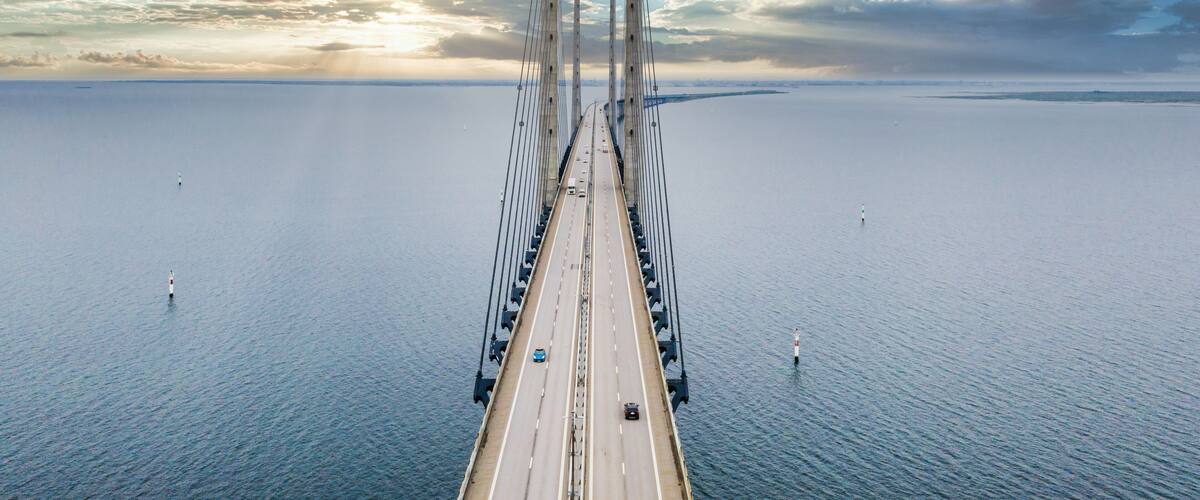 A large suspension bridge spanning a wide body of water with a cloudy sky above.