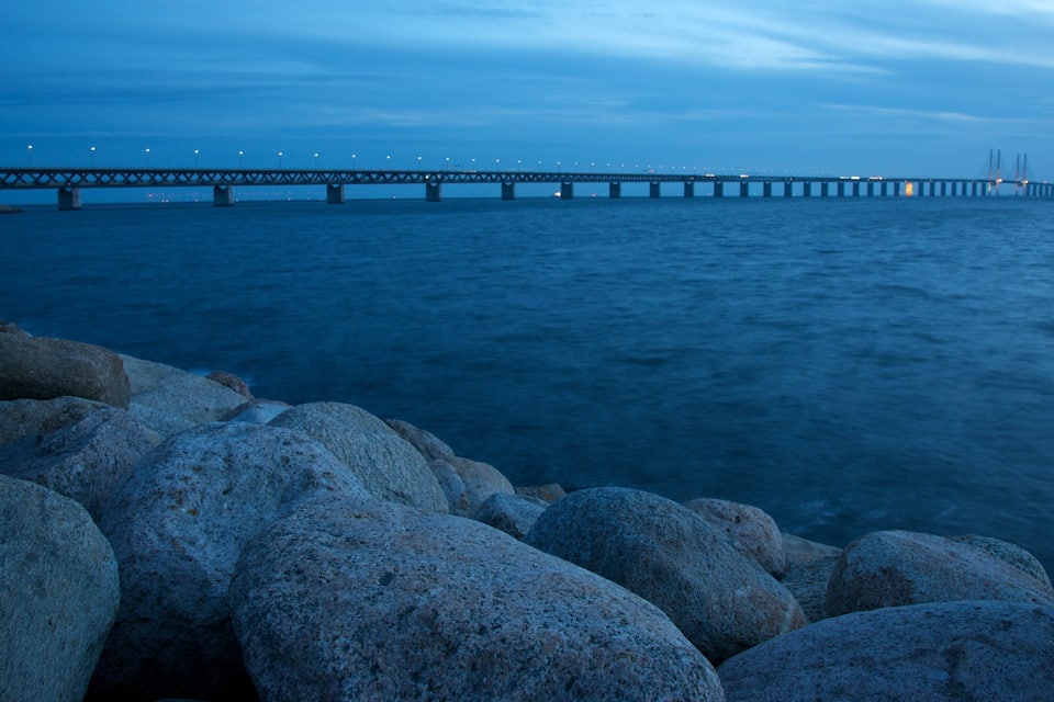 Een brug over water met grote rotsen op de voorgrond.