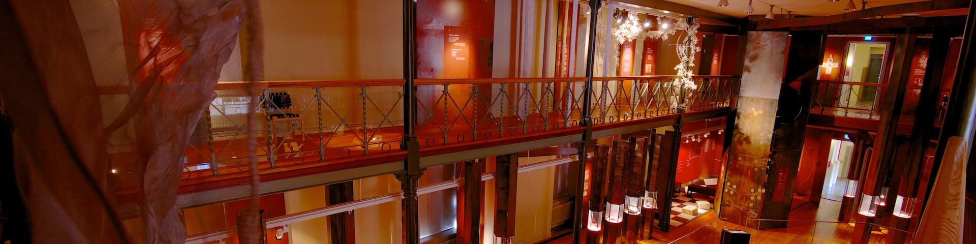 Interior con vigas de madera, paneles de vidrio y luminarias iluminadas.