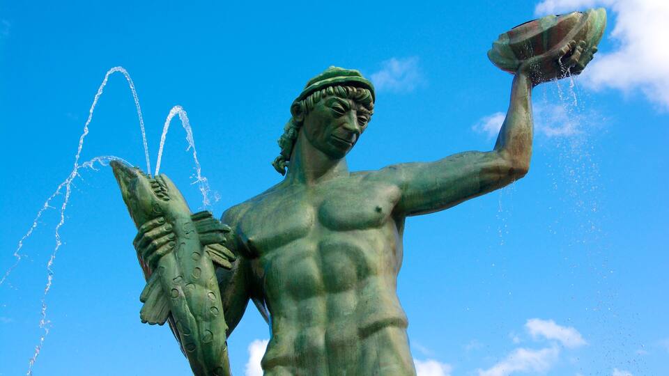 Estátua de uma figura musculosa segurando um peixe e derramando água.