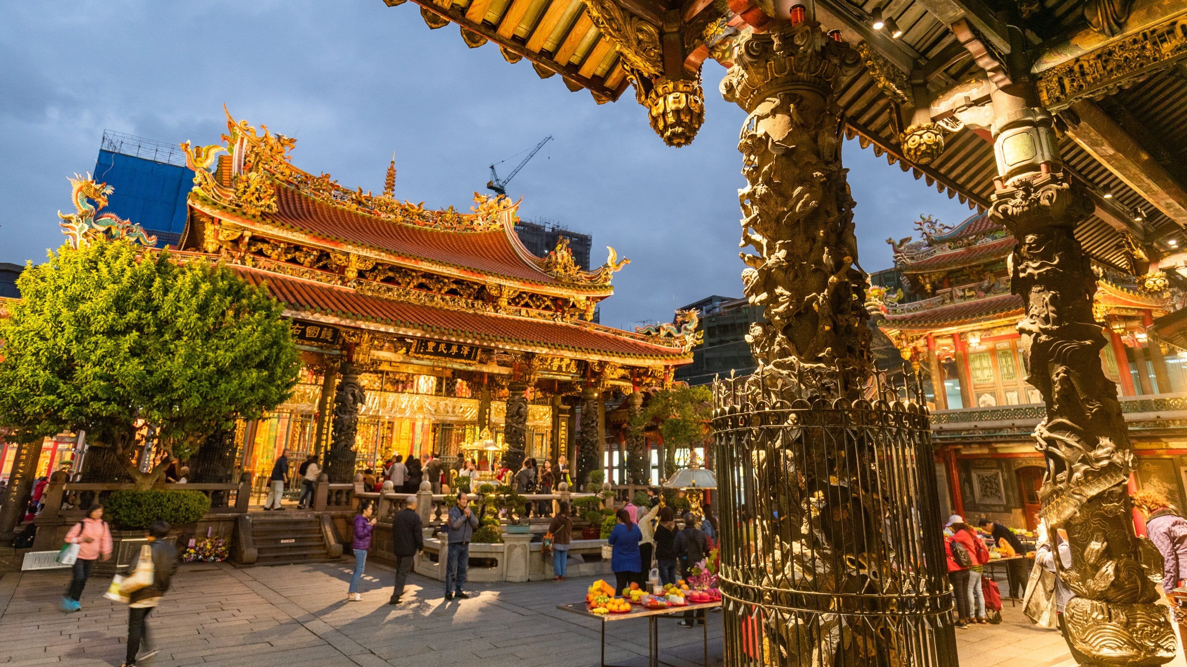 A traditional temple with ornate architecture and a bustling market area in front.