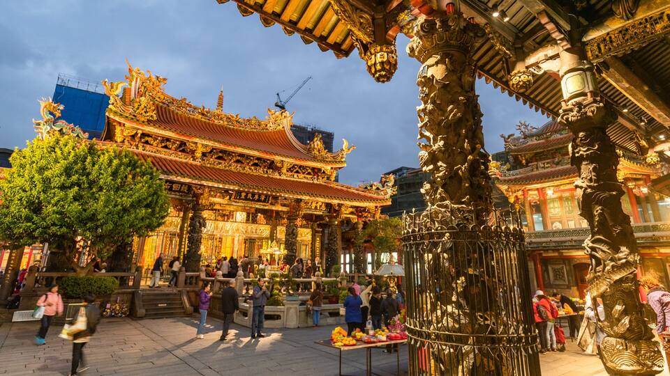 A traditional temple with ornate architecture and a bustling market area in front.
