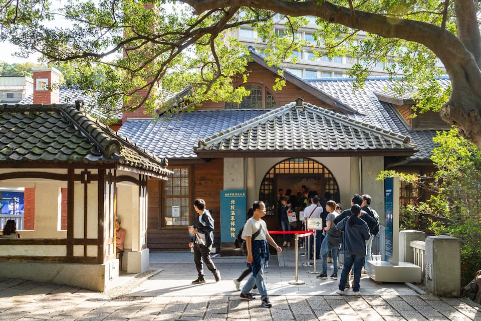 A traditional Japanese building with tiled roofs and a wooden gate.