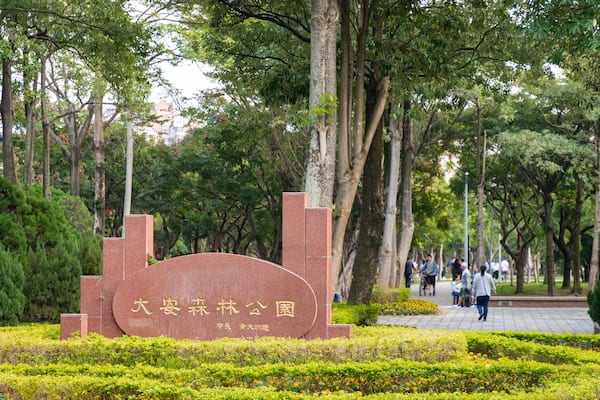 A park with a large stone monument surrounded by lush greenery and trees.