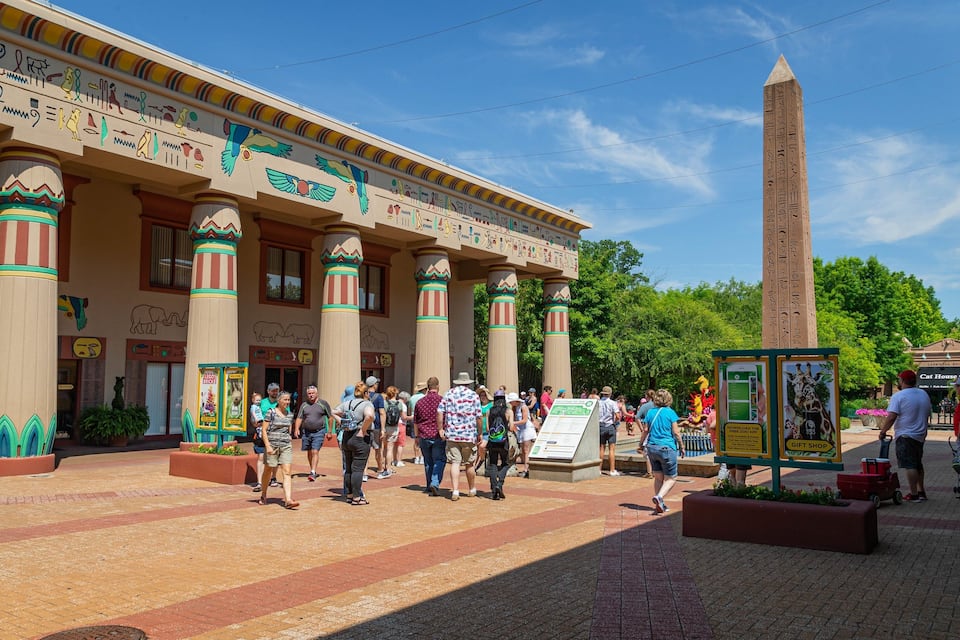 En bygning med egyptiske søjler og hieroglyffer, en høj obelisk og en menneskemængde.