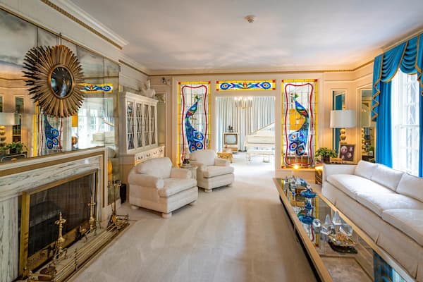 A luxurious living room with a grand fireplace, elegant furniture, and colorful stained glass windows.