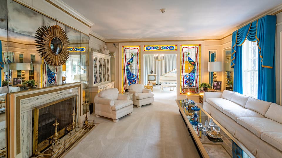 Un salon luxueux agrémenté d’une imposante cheminée, de meubles élégants et de vitraux aux couleurs vives.