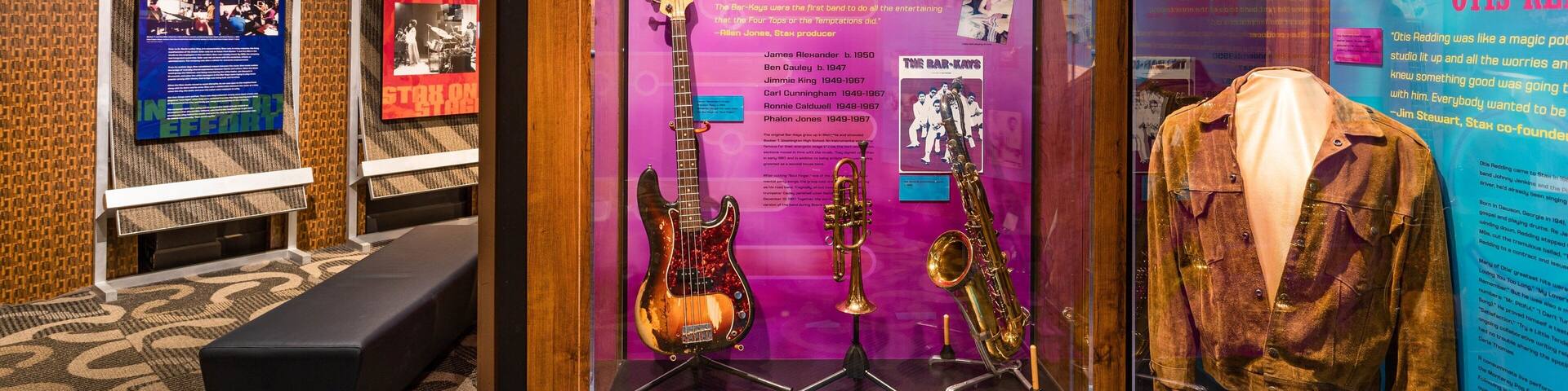 Una vitrina con recuerdos de The Bar-Kays, incluyendo guitarras, un saxofón y una chaqueta.