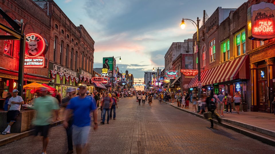 A bustling street lined with historic buildings and neon signs, indicating a lively urban area.