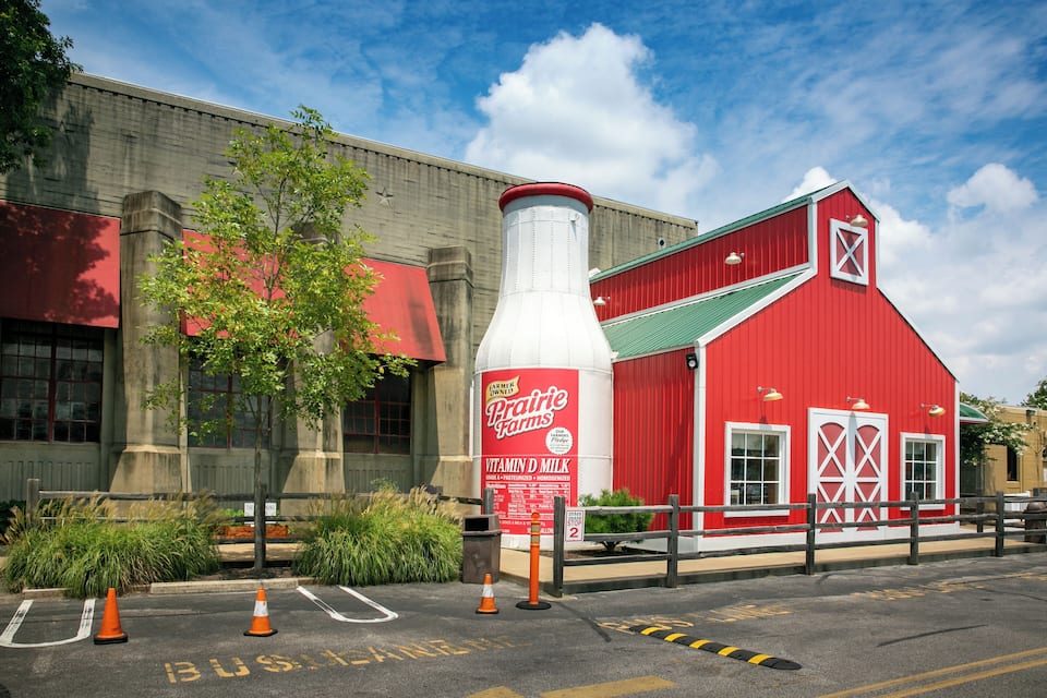 A red barn with a large white silo labeled "Prairie Farms" and a tree in front.