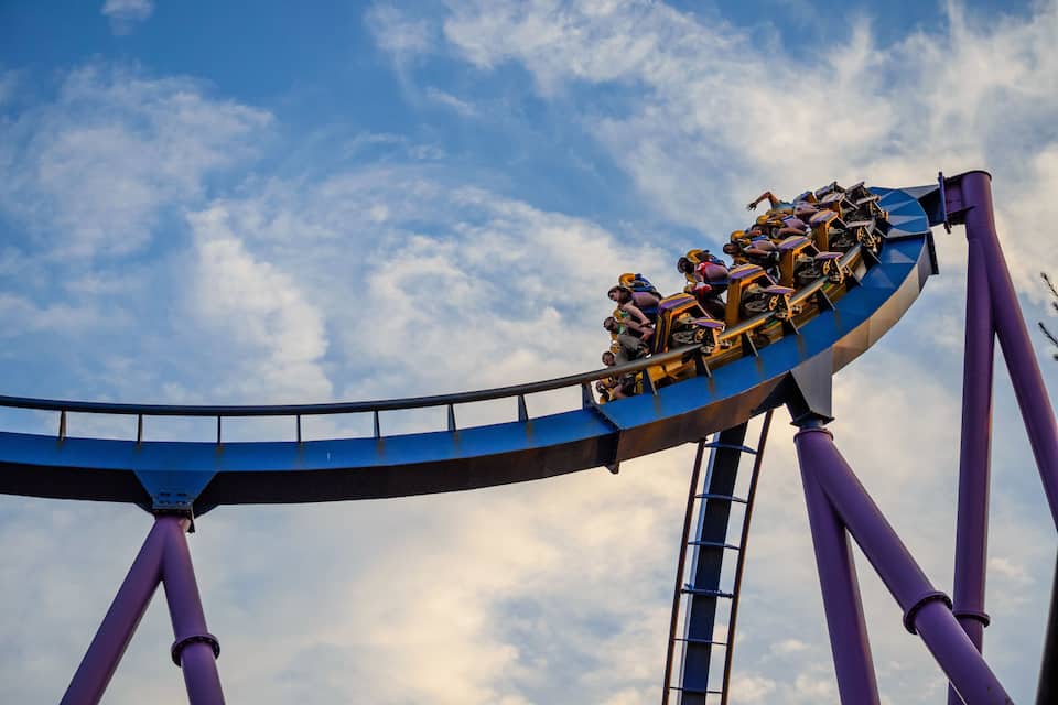A roller coaster in a loop against a partly cloudy sky.