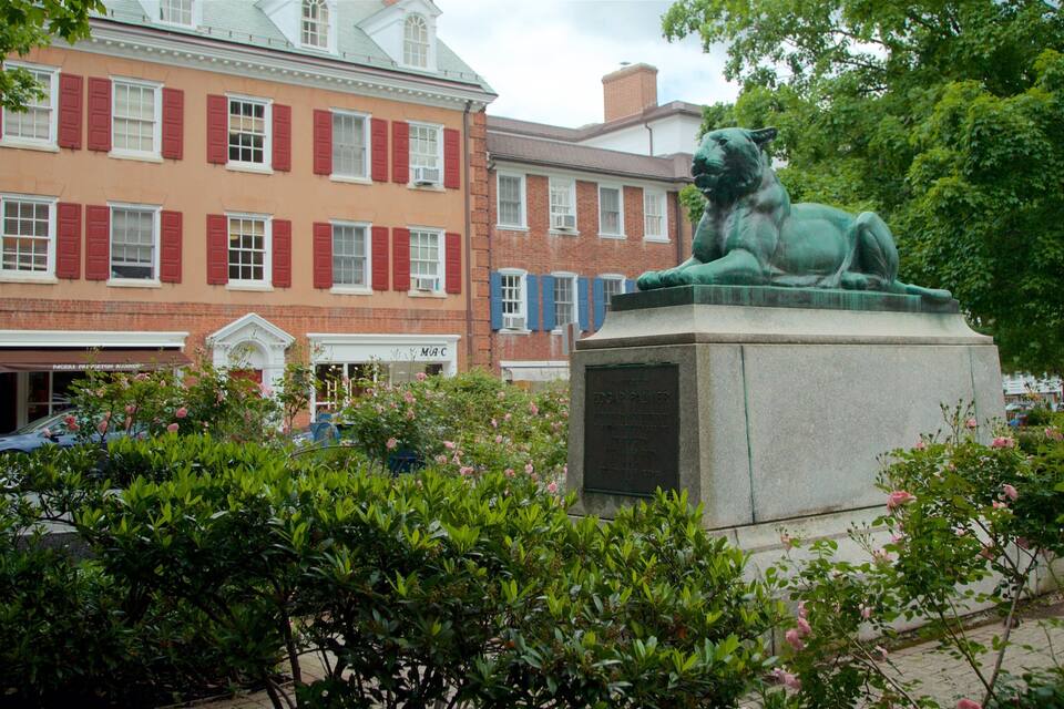 Una estatua de león en un parque con un edificio al fondo.