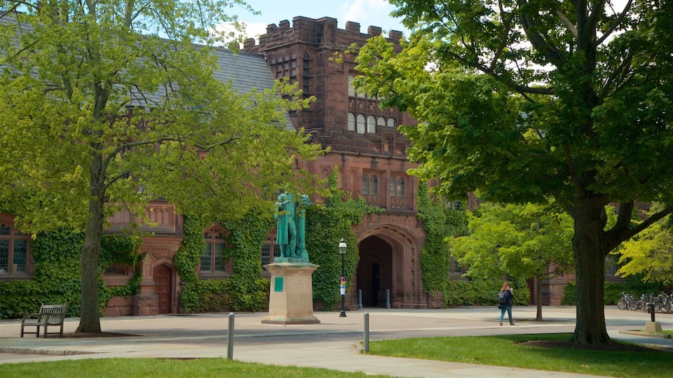 A historic building with ivy-covered walls and a statue in front.