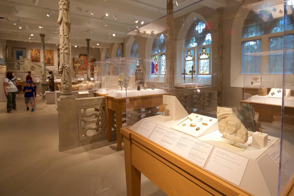 An interior museum with glass display cases containing artifacts and sculptures.