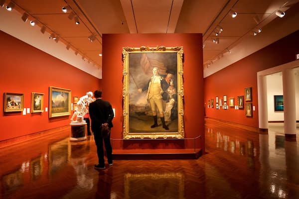 An art gallery with a large historical painting and several smaller framed artworks on the walls.