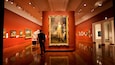 An art gallery with a large historical painting and several smaller framed artworks on the walls.