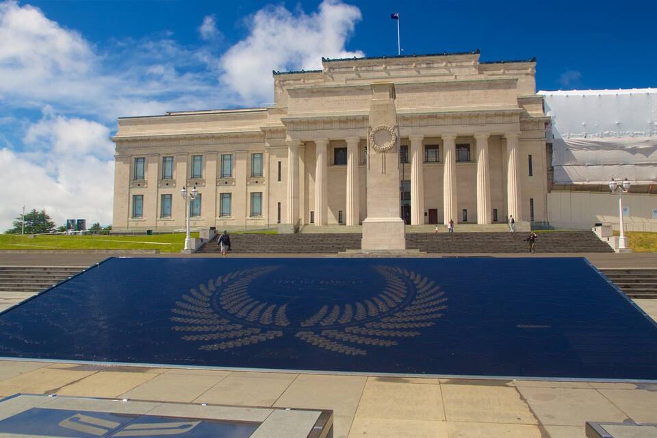 A large building with classical architecture, a prominent entrance, and a large emblem on the ground.
