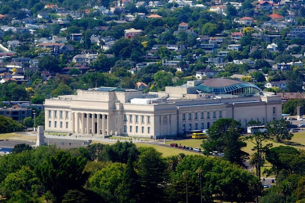 A large government building with a dome, surrounded by a residential area and greenery.