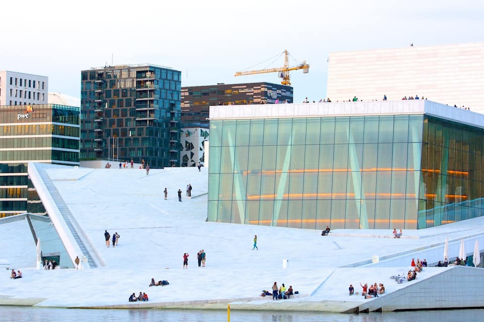 A modern architectural structure with a glass facade, a large open plaza, and a construction crane in the background.