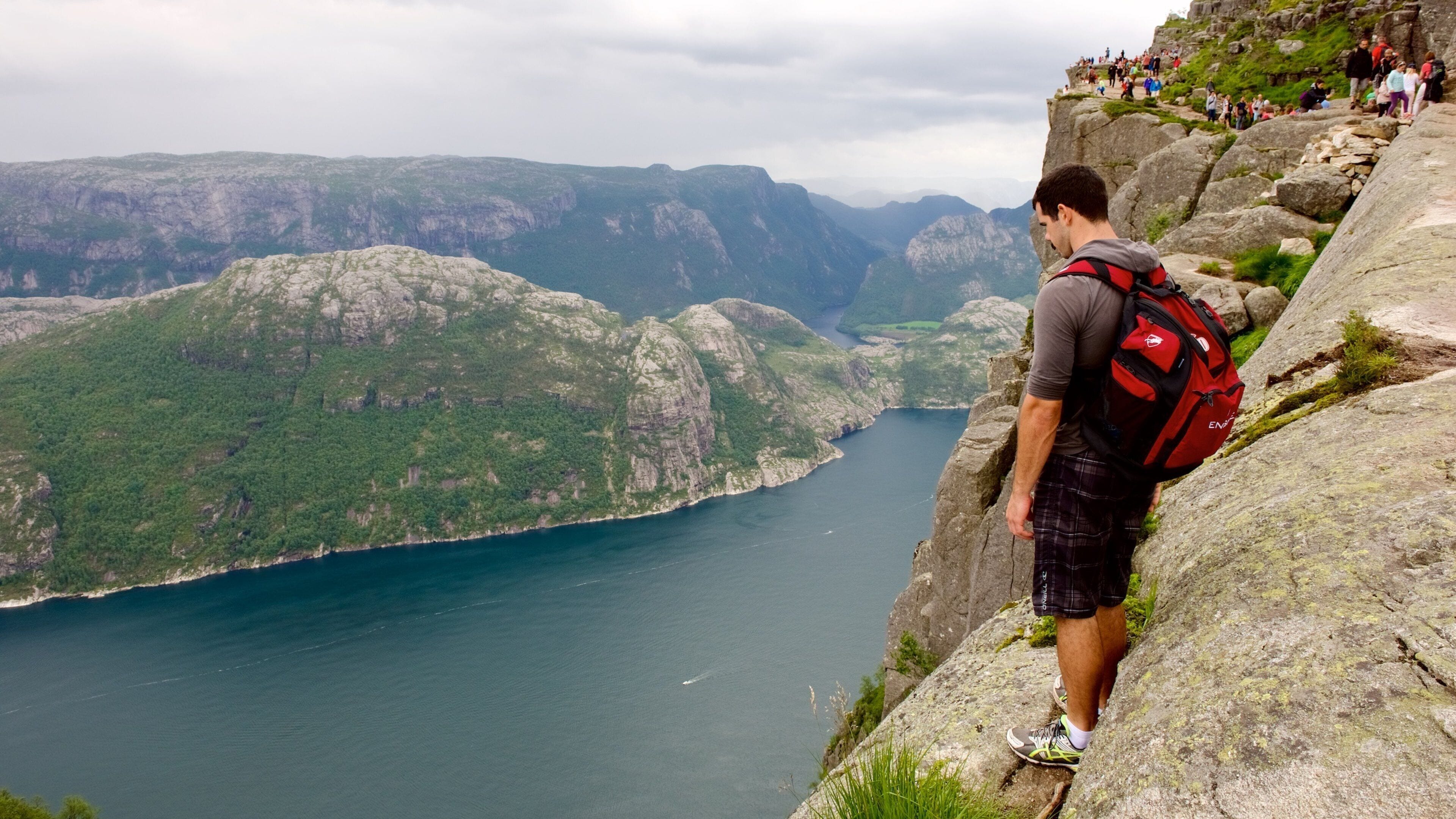 Preikestolen featuring mountains and a lake or waterhole as well as an individual male