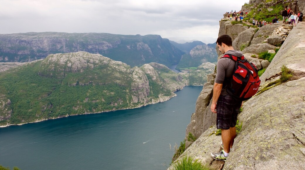 Preikestolen featuring mountains and a lake or waterhole as well as an individual male