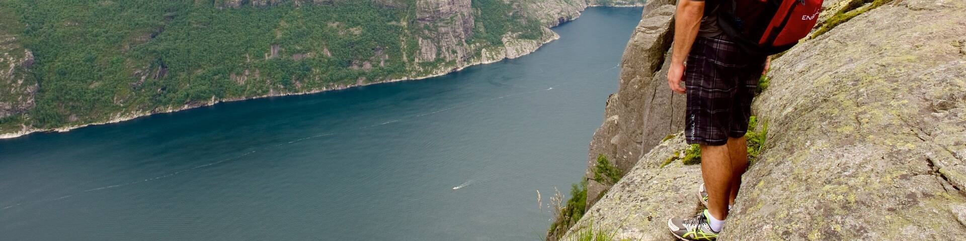 Preikestolen featuring mountains and a lake or waterhole as well as an individual male