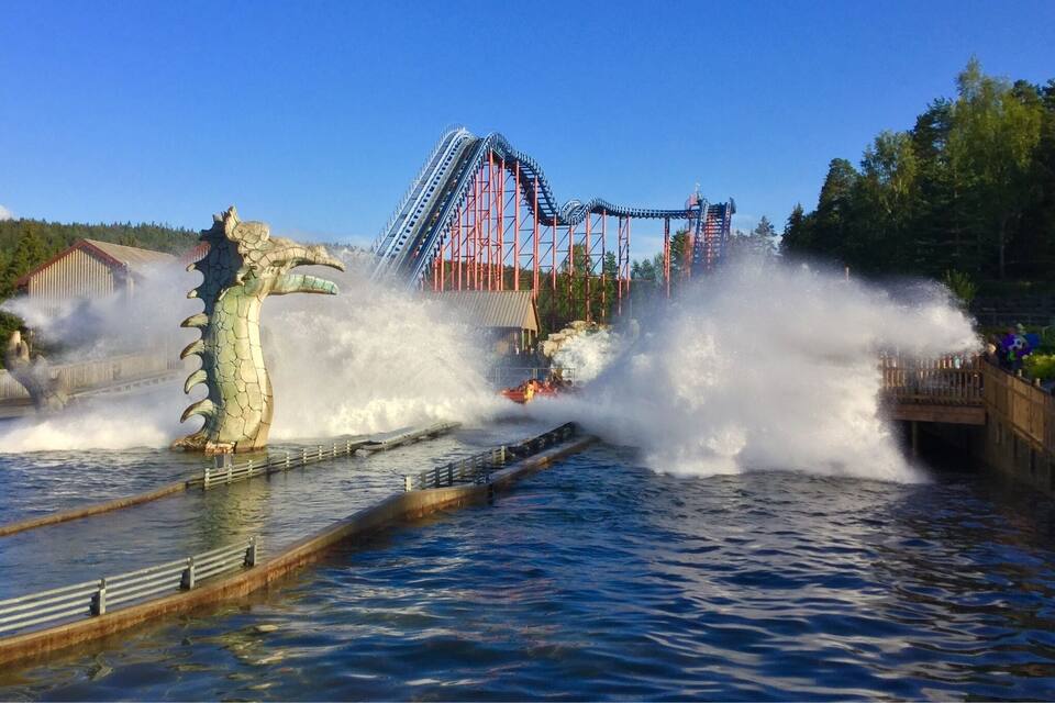 A water park with a dragon statue and a roller coaster in the background.