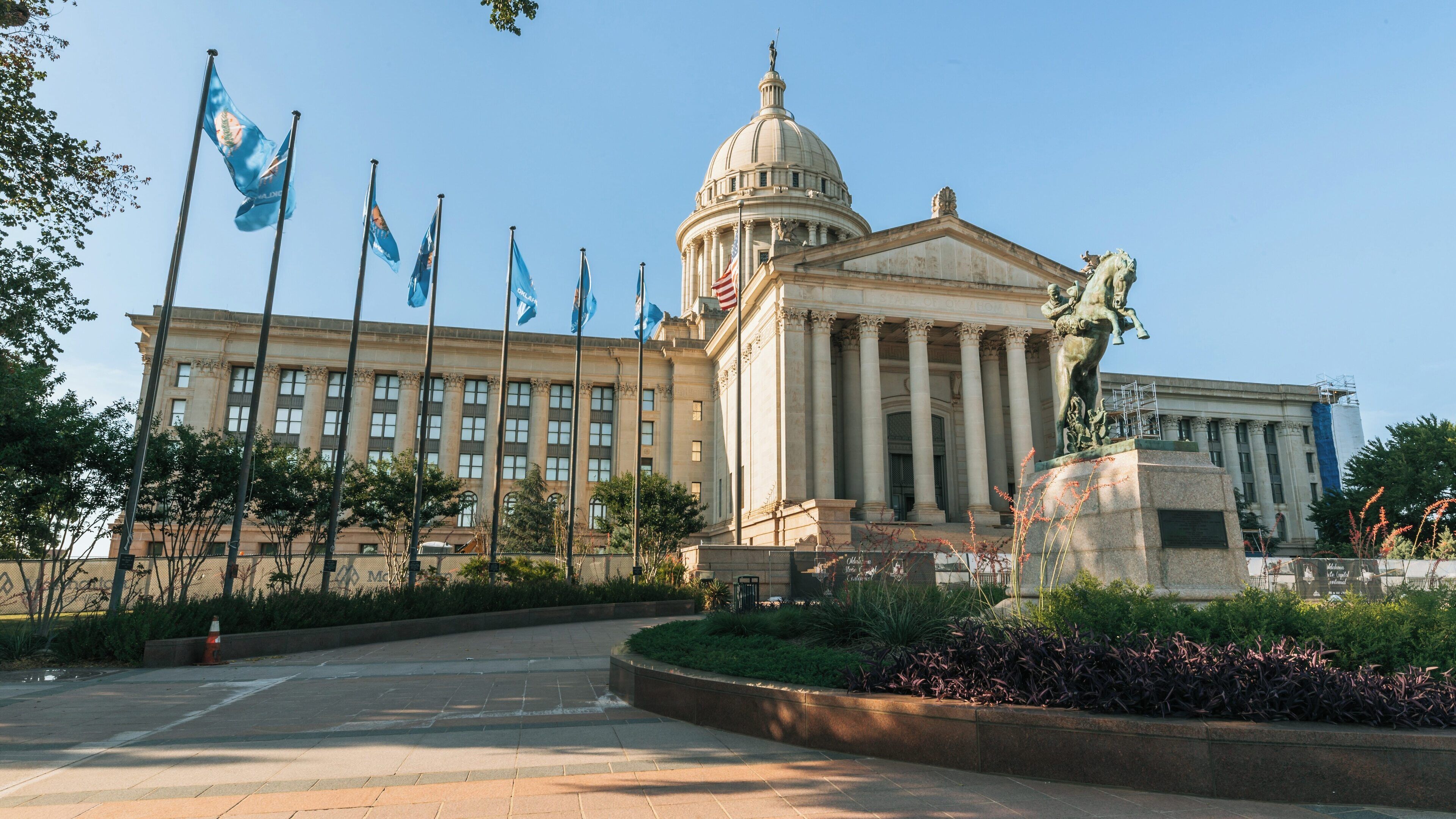 Oklahoma State Capitol stands majestically in Downtown Oklahoma City, showcasing historic architecture and vibrant flags against a clear blue sky