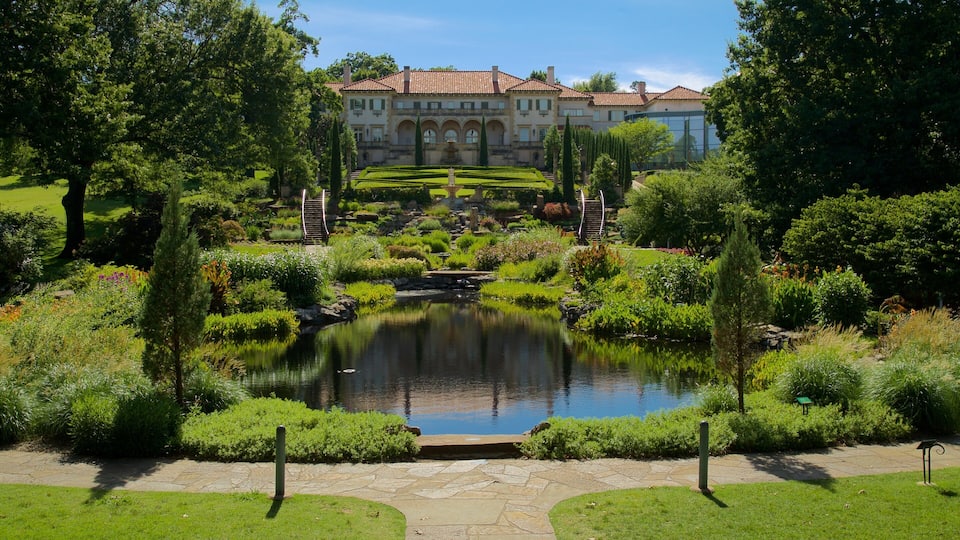A landscaped garden with a pond, manicured lawns, and a large building in the background.