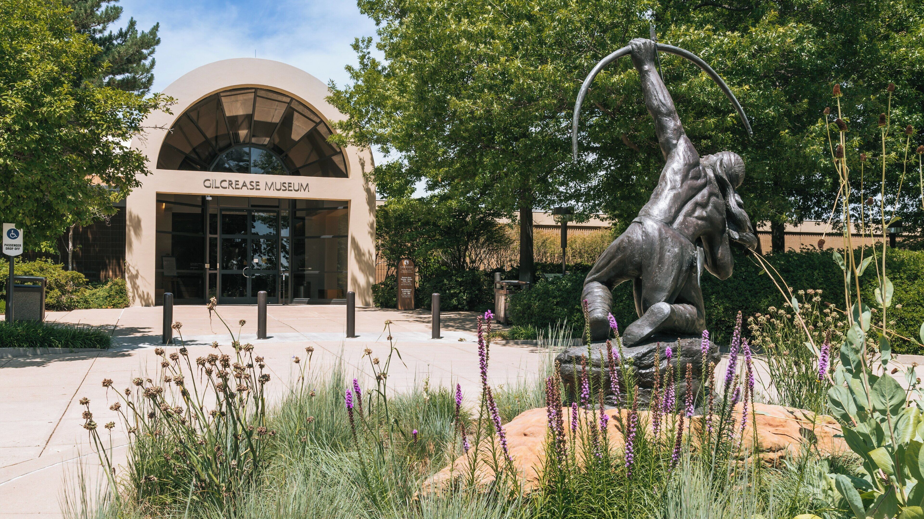 Gilcrease Museum features outdoor sculpture and beautiful landscaping in Tulsa, Oklahoma under clear skies