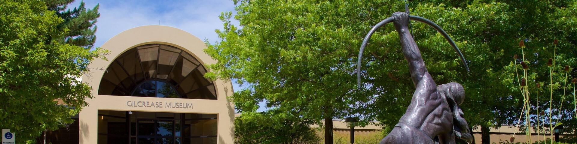 The Gilcrease Museum with a statue of a man holding a ring in front of it.