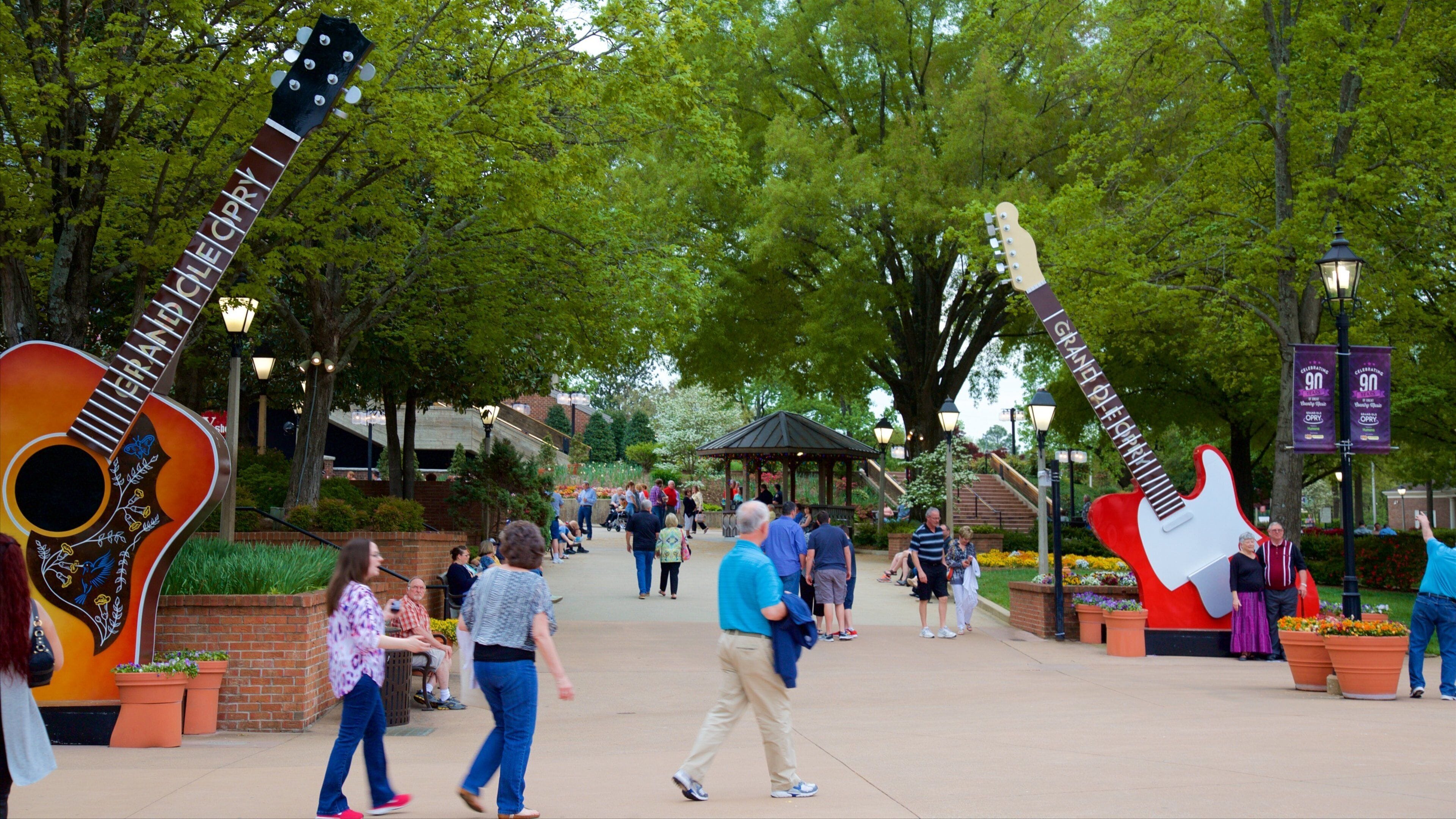 Ein Park mit großen Gitarrenskulpturen, Spaziergängern und einem Musikpavillon.