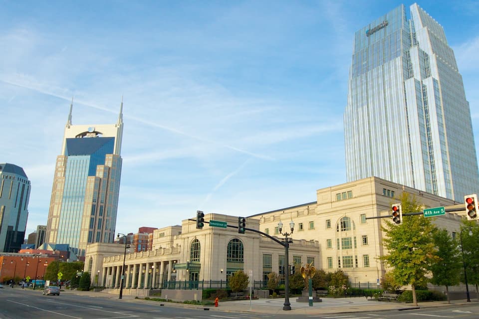 A city intersection with modern skyscrapers, a historic building, and a traffic light.