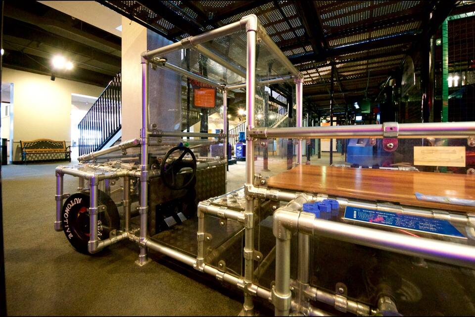 A metal structure with a steering wheel and a sign indicating a lever is needed to lower or raise it.