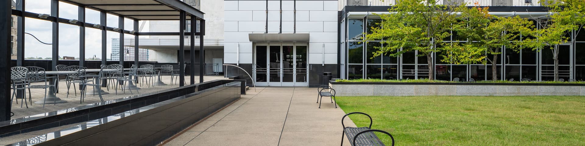 The exterior of the Frist Art Museum with a covered outdoor seating area and a lawn.