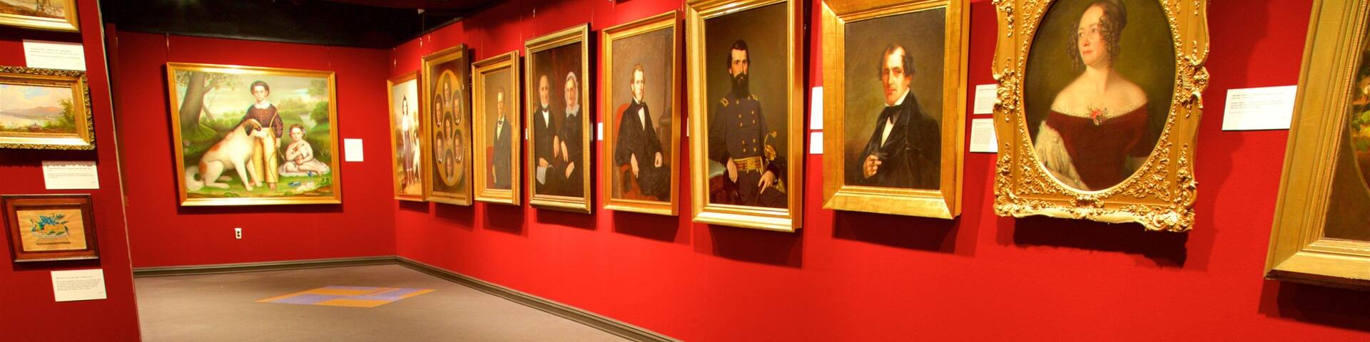 An art gallery with red walls and a red bench.
