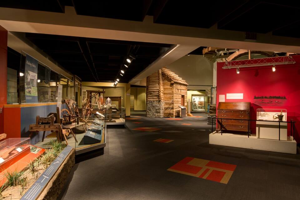 An indoor museum exhibit with historical artifacts, including wooden tools and a stone structure.