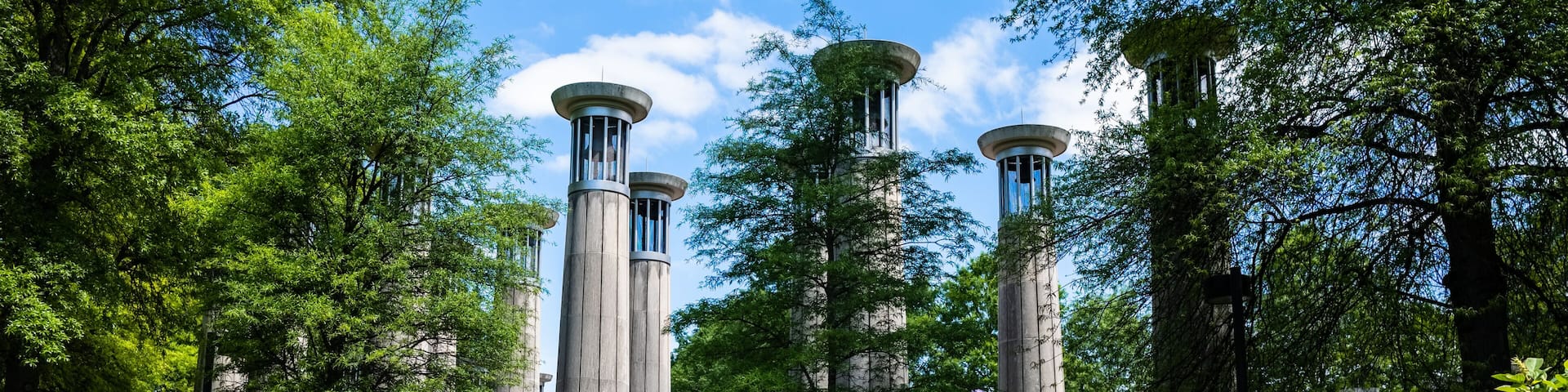 A garden with tall stone columns, purple flowers, and lush green trees.