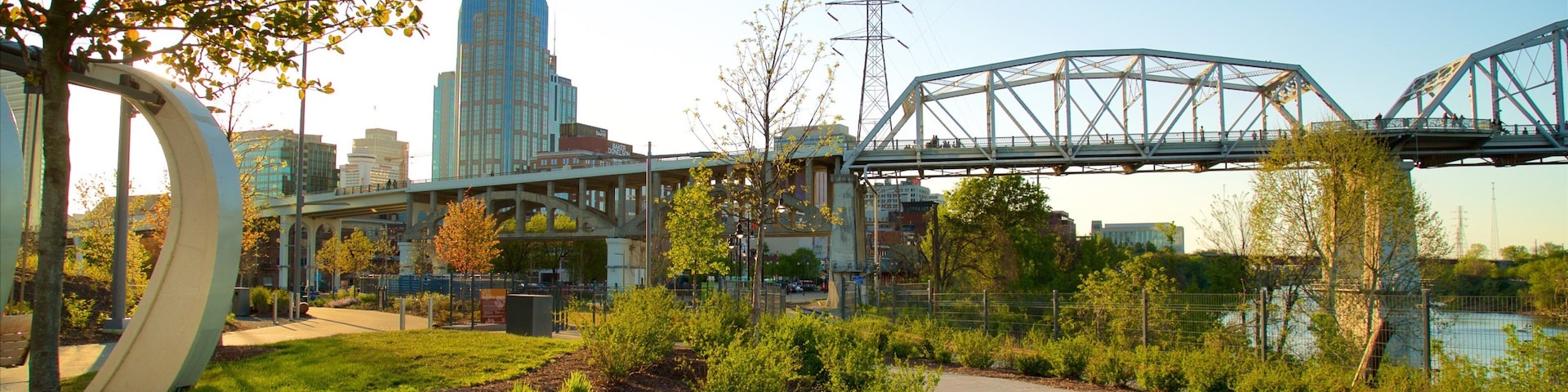 Parque de Riverfront que inclui uma ponte, um pôr do sol e um jardim