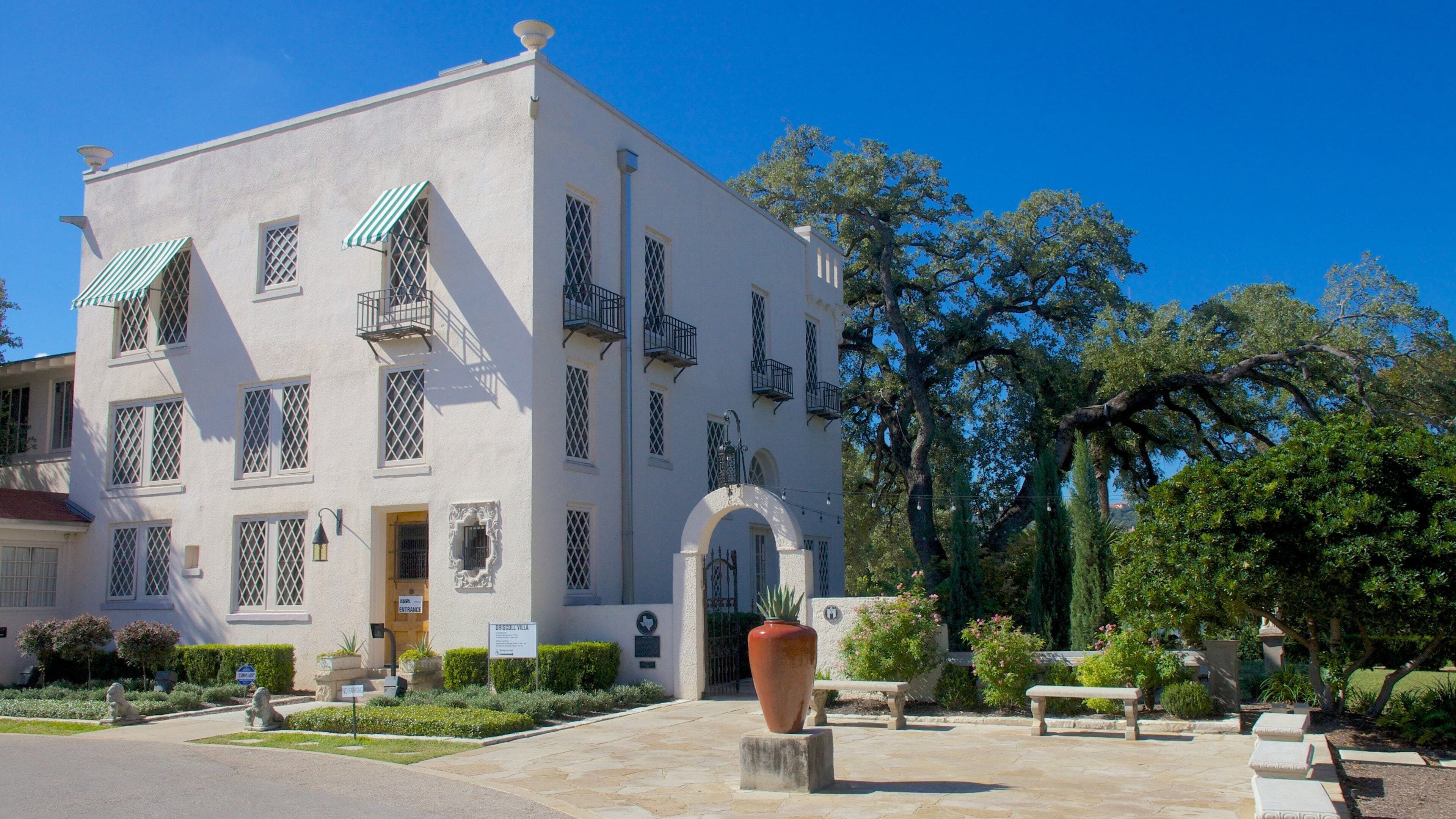 A white building with green awnings and a large arched entrance.