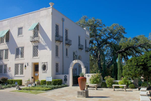 Edifício branco com toldos verdes e uma grande entrada em arco.