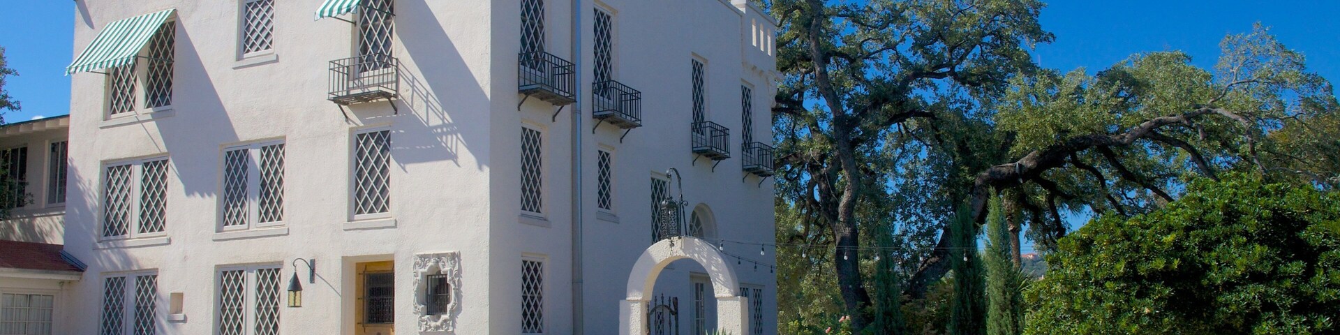 Edifício branco com toldos verdes e uma grande entrada em arco.