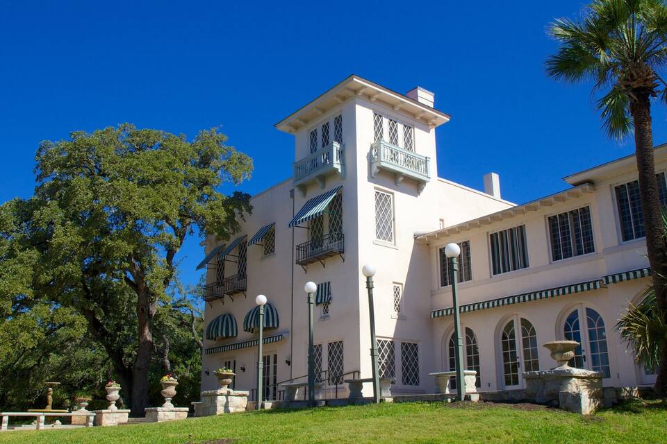 A large, white building with a tower, surrounded by trees and a well-maintained lawn.
