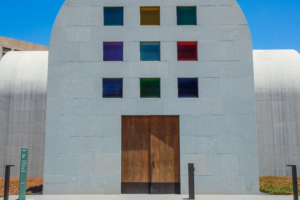Um edifício moderno com porta de madeira e janelas coloridas.