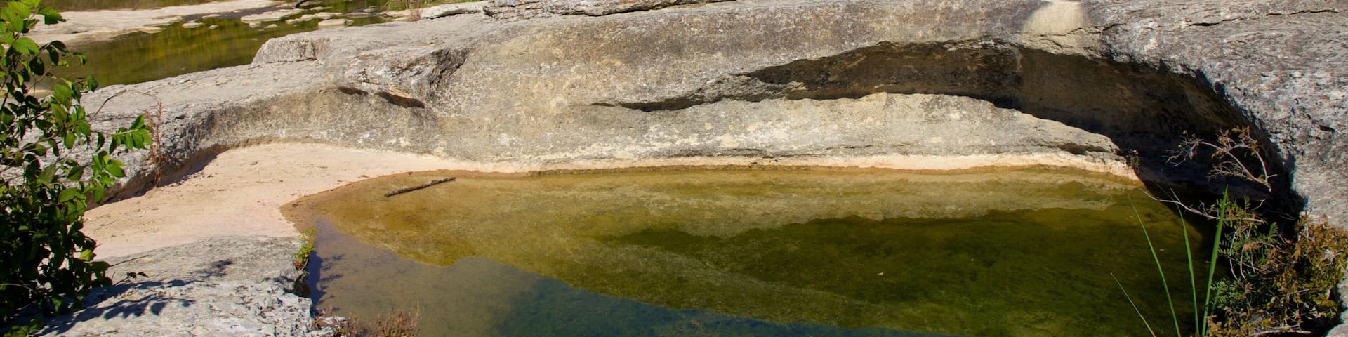 A natural rock formation with a clear water pool.